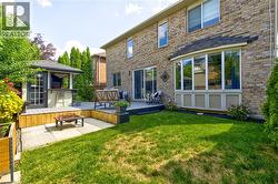 Brick exterior featuring a multi-level deck, a built-in gazebo with a bar, a bay window, and sliding glass doors - 