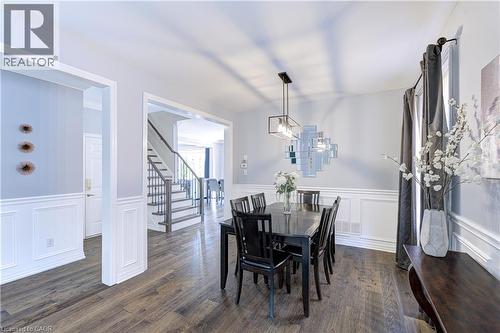 Formal dining area featuring wood-finish flooring, wainscoting, and a linear pendant light fixture - 1406 Marshall Crescent, Milton, ON 
