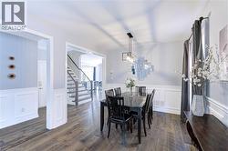 Formal dining area featuring wood-finish flooring, wainscoting, and a linear pendant light fixture - 