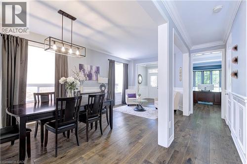 Open-concept interior featuring wood-finish flooring, a linear pendant light fixture, extensive crown molding, and wainscoting details - 1406 Marshall Crescent, Milton, ON 