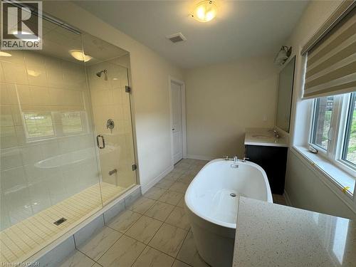Spacious bathroom featuring a frameless glass shower enclosure, a freestanding soaking tub, a single vanity with a solid surface countertop, and large format floor tiles - 10 Guernsey Drive Unit# Upper, Kitchener, ON 