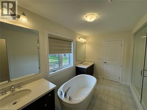 Bathroom featuring a freestanding soaking tub, dual vanities with quartz countertops, a glass-enclosed shower, and patterned tile flooring - 10 Guernsey Drive Unit# Upper, Kitchener, ON 