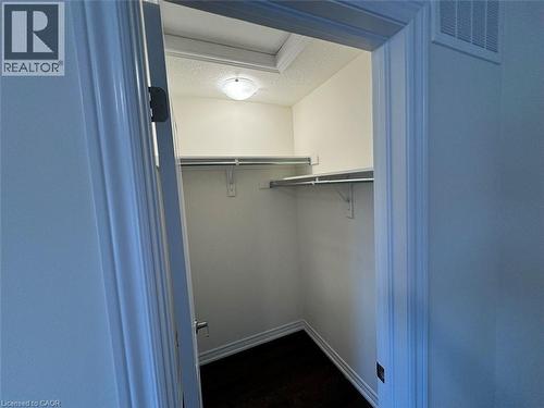 Walk-in closet featuring white walls, dark wood-finish flooring, and a ceiling-mounted light fixture - 10 Guernsey Drive Unit# Upper, Kitchener, ON 