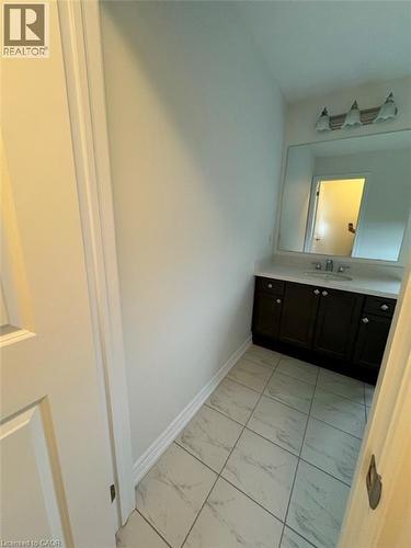 Dark wood-finish vanity with a light-toned countertop, integrated sink, and wall-mounted mirror - 10 Guernsey Drive Unit# Upper, Kitchener, ON 