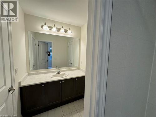 Bathroom vanity with a white countertop and an integrated sink, dark wood-finish cabinetry, a large mirror, and a four-light fixture - 10 Guernsey Drive Unit# Upper, Kitchener, ON 