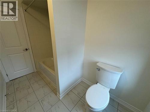 Bathroom featuring a white toilet, tile flooring, and a shower-tub combination - 10 Guernsey Drive Unit# Upper, Kitchener, ON 
