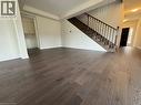 Expansive room featuring wide plank wood-finish flooring, a grand staircase with dark wood banister and balusters, a tray ceiling, and a built-in cabinetry niche - 10 Guernsey Drive Unit# Upper, Kitchener, ON 