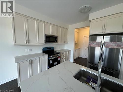 Modern kitchen featuring white shaker cabinetry, stainless steel appliances, a built-in microwave, and stone countertops - 10 Guernsey Drive Unit# Upper, Kitchener, ON 
