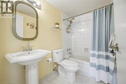 Full bathroom featuring a pedestal sink with chrome faucet, a toilet, and a combination tub and shower with white subway tile surround - 