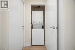 Dedicated laundry closet featuring a white stacked washer and dryer, light wood-finish flooring, and white interior doors - 
