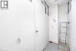 Dedicated storage unit featuring a metal door, concrete flooring, and an overhead lighting fixture - 