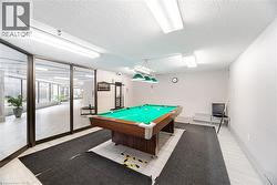 Recreational room featuring a billiard table with green felt and wood-finish frame, overhead pendant lighting, and a cue rack - 