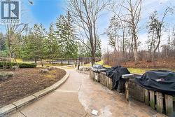 Outdoor grilling station featuring a paver patio and stone-clad base, bordered by a concrete pathway - 