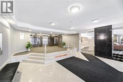 Lobby area featuring light-toned floor tiling, multiple recessed lights, and a prominent black stone-finish accent wall - 