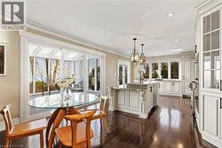 Spacious kitchen featuring rich wood-finish flooring and extensive white cabinetry - 
