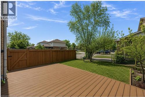 Expansive composite deck featuring a privacy fence with gate, manicured lawn, and mature trees - 125 Terni Boulevard, Hamilton, ON 