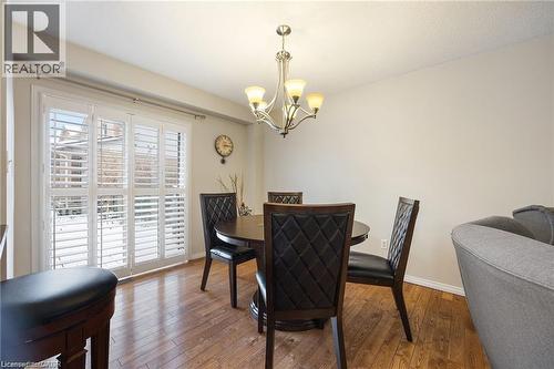 Dining area featuring wood-finish flooring, a contemporary chandelier, and sliding glass doors with interior plantation shutters - 125 Terni Boulevard, Hamilton, ON 