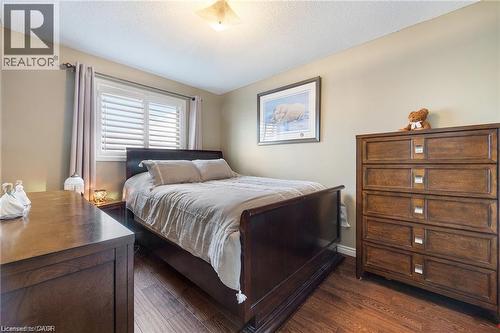 Bedroom featuring wood-finish flooring, neutral wall tones, and a window with white plantation shutters - 125 Terni Boulevard, Hamilton, ON 