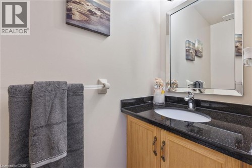 Vanity with wood-finish cabinetry, dark speckled countertop, undermount sink, and polished chrome faucet - 125 Terni Boulevard, Hamilton, ON - Indoor Photo Showing Bathroom