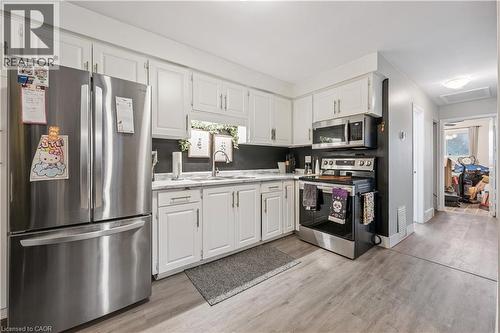 Kitchen featuring white cabinetry, stainless steel appliances, light-toned wood-finish flooring, and a window above the sink - 35 Vicmount Drive, Kitchener, ON 