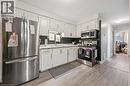 Kitchen featuring white cabinetry, stainless steel appliances, light-toned wood-finish flooring, and a window above the sink - 35 Vicmount Drive, Kitchener, ON 