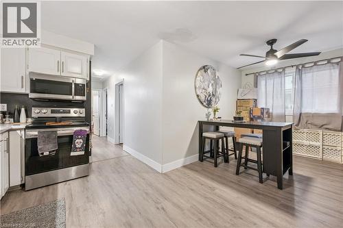 Contemporary kitchen featuring white cabinetry, stainless steel appliances, and wood-finish flooring - 35 Vicmount Drive, Kitchener, ON 