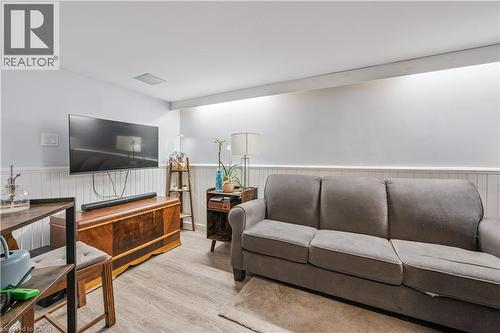 Living area featuring wood-finish flooring, white shiplap wainscoting, a wall-mounted television, and integrated ceiling lighting - 35 Vicmount Drive, Kitchener, ON 