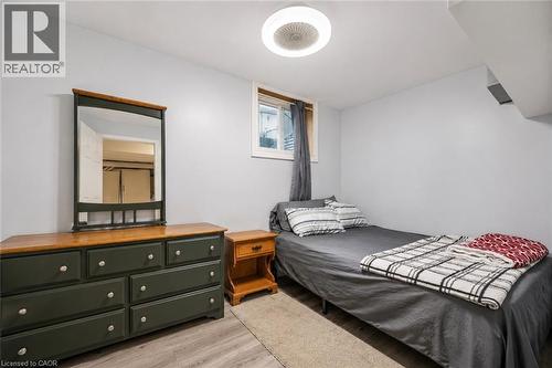 Room featuring light gray walls, wood-finish flooring, and a ceiling-mounted light fixture. Digitally enhanced - 35 Vicmount Drive, Kitchener, ON 