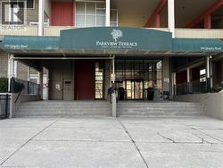 Building entrance featuring a multi-step concrete staircase, an overhead green awning, and a glass-paneled double-door entry - 