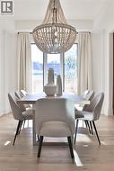 Dining area with a beaded chandelier, light wood-finish flooring, and natural light from large windows - 