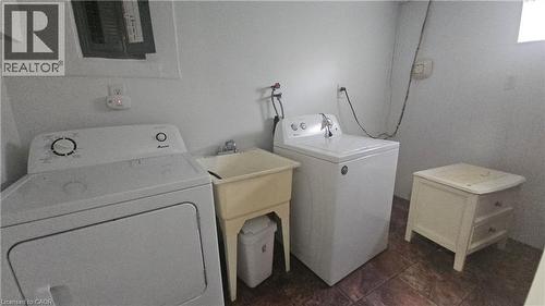 Dedicated utility area featuring a ceramic utility sink, white walls, and durable floor tiling - 58 Belwood Crescent, Kitchener, ON 
