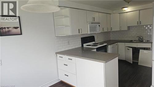 Kitchen featuring white cabinetry, gray countertops, white subway tile backsplash, and dark wood-finish flooring - 58 Belwood Crescent, Kitchener, ON 