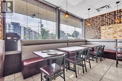 Commercial dining space featuring large storefront windows, tiled flooring, upholstered booth seating, decorative wall paneling, and pendant lighting fixtures - 