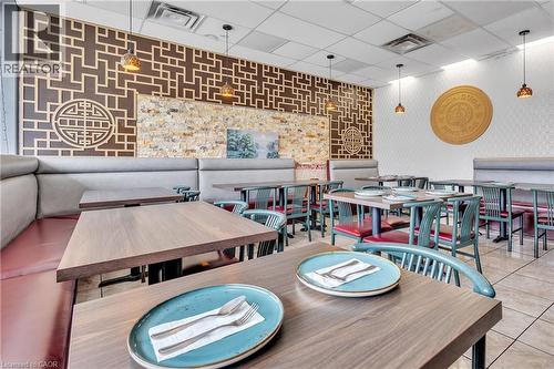 Spacious dining area featuring booth seating, wood-finish tables, pendant lighting, textured wall accents, and tiled flooring - 155 Highland Road E, Kitchener, ON 