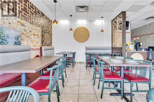 Spacious dining area featuring booth seating, decorative wall panels, pendant lighting, and tiled flooring - 155 Highland Road E, Kitchener, ON 