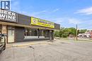 Commercial building featuring a brick facade with horizontal paneling and prominent storefront windows - 155 Highland Road E, Kitchener, ON 