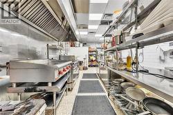 Commercial-grade kitchen featuring stainless steel appliances, a large griddle, extensive stainless steel shelving, and durable non-slip floor mats - 