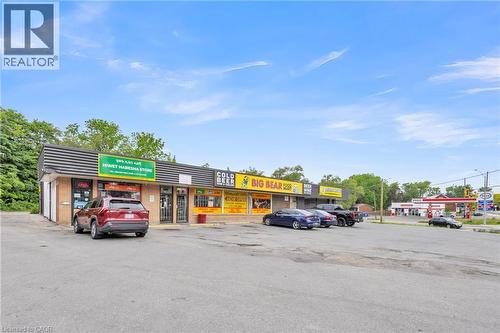 Commercial retail building with a striped awning, multiple storefronts, and an expansive paved parking area - 155 Highland Road E, Kitchener, ON 