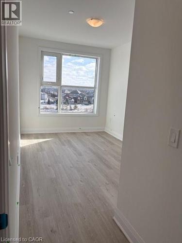 Bright room featuring a large multi-pane window, wood-finish flooring, white baseboards, and a semi-flush ceiling light fixture - 1936 Rymal Road E Unit# 516, Hannon, ON - Indoor Photo Showing Other Room