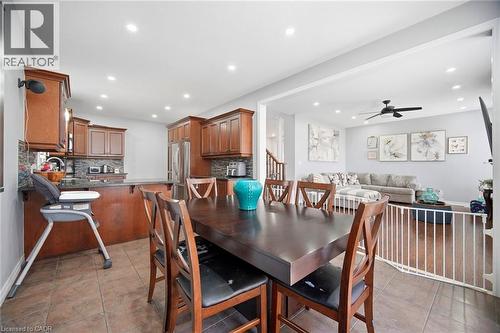 Open-concept kitchen and dining area featuring rich wood cabinetry, stone-finish countertops, and tile flooring - 79 Garinger Crescent, Hamilton, ON 