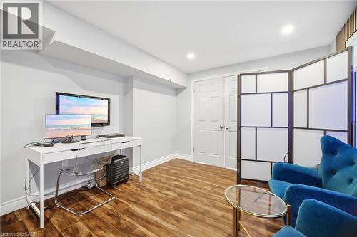 Versatile room featuring wood-finish flooring, white baseboards, and light gray wall paint - 79 Garinger Crescent, Hamilton, ON 
