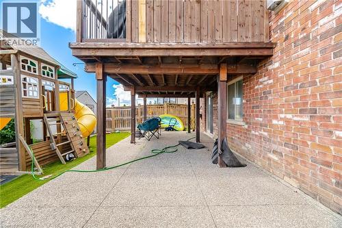 Ground-level patio featuring an exposed aggregate surface and overhead deck structure - 79 Garinger Crescent, Hamilton, ON 