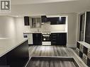 Modern kitchen featuring dark cabinetry, light countertops, wood-finish flooring, a full suite of appliances including a dishwasher and range, and recessed lighting - 134 E Bridgeport Road E Unit# Lower, Waterloo, ON 