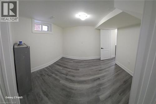 Light-filled room featuring wood-finish flooring, white baseboards, a single casement window, and a white interior door with black hardware - 134 E Bridgeport Road E Unit# Lower, Waterloo, ON 