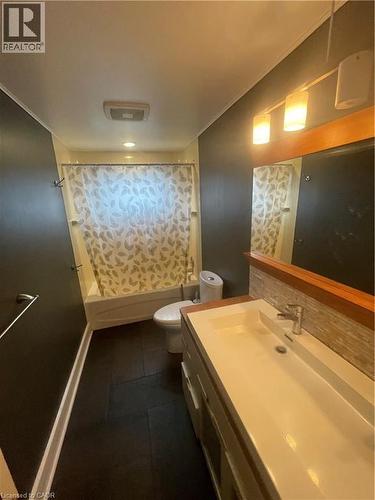 Bathroom featuring a vanity with integrated sink, a rectangular mirror with wood-tone framing, and modern wall sconces - 134 Bridgeport Road E Unit# Upper, Waterloo, ON 