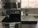 Kitchen featuring stainless steel appliances, speckled stone countertops, and light wood-finish cabinetry - 280 Lester Street Unit# 607, Waterloo, ON 