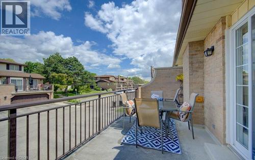 Spacious outdoor terrace with a concrete surface, featuring a black metal railing and a beige brick exterior - 458 Beechwood Place Unit# 3, Waterloo, ON - Outdoor With Exterior