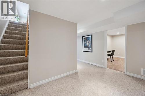 Carpeted staircase with wooden handrail, leading to a carpeted lower level with light-toned walls and white trim - 2 Keewatin Avenue, Kitchener, ON 