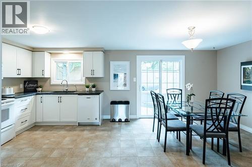 Kitchen featuring white cabinetry, dark countertops, white dishwasher, and tiled flooring - 28 Mcgibbon Court, Kitchener, ON 