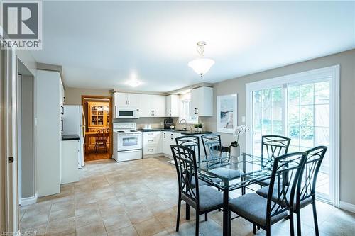 Kitchen and dining area featuring tile flooring, white cabinetry, a white appliance package, and a sliding glass door providing natural light - 28 Mcgibbon Court, Kitchener, ON 